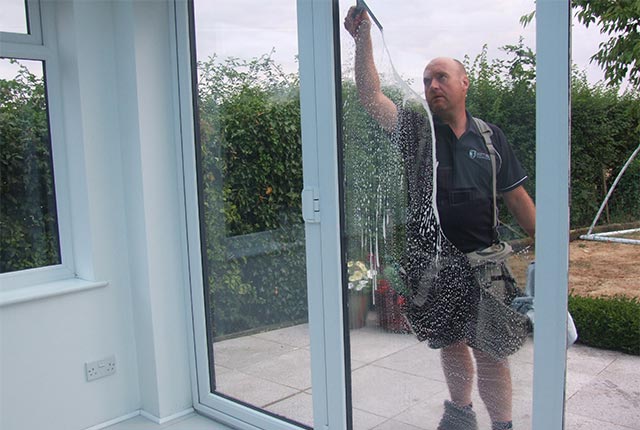 Window cleaner wiping down conservatory doors